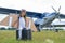 A little girl plays a pilot on the background of a small plane with a propeller. A child in a suit with cardboard wings