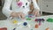 A little girl plays with plasticine, rolls balls, there are figures and colored pencils on the desktop, the development