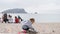 Little girl plays in the sand on the beach. Two-year-old child in a denim jacket playing with plastic toys on a sandy