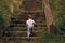 Little girl with a ponytail and a jumpsuit climbing up the old overgrown stairs.