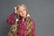 Little girl with ponytails standing isolated on grey scratching head pensive