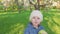 Little girl portrait eating green apple outdoor. A girl with an apple on the background of flowering gardens.