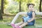 Little girl portrait seated on park bench and  holding a blue elephant doll at hand