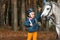 Little girl portrait, stands next to a white pony close-up on the background of nature. Jockey, epodrome, horseback riding