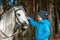 Little girl portrait, stands next to a white pony close-up on the background of nature. Jockey, epodrome, horseback riding