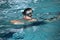 Little girl practicing flutter kick with kick board in indoor swimming pool