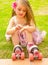 Little girl preschool beginner in roller skates, putting some grass in her hand, grass background