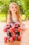 Little girl preschool sitting on ground wearing her roller skates, in a garden background