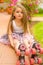 Little girl preschool sitting on ground wearing her roller skates, in a garden background