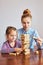 Little girl preschooler and her elder sister playing together with wooden blocks game toy