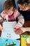 Little girl preschooler learning to write letters with help of her mother