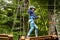 Little girl preschooler wearing full climbing harness having fun time in the rope park using carabiner and other safety