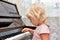 A little girl presses her fingers on the white keys of the piano. Teaching children at a music school