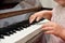 A little girl presses her fingers on the white keys of the piano. Teaching children at a music school