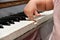 A little girl presses her fingers on the white keys of the piano. Teaching children at a music school