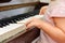 A little girl presses her fingers on the white keys of the piano. Teaching children at a music school