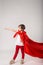 Little girl pretend superhero in red cape