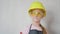 Little girl in protective helmet and goggles, thinks about the project. Childhood, construction, architecture, building