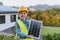 Little girl with protective helmet and reflective vest holding photovoltaics solar panel. Alternative energy, saving