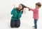 A little girl pulls her older sister hair isolated on white