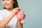 A little girl puts a coin in a piggy bank. The concept of teaching children personal finance and saving.