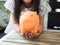 Little girl putting coin into piggy bank for saving with pile of