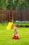 Little girl in the rain in a red basin on grass