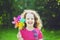 Little girl with rainbow pinwheel toy in summer park. Eco, trave