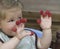 Little girl with raspberry on fingers