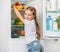 Little girl reaching apples in fridge