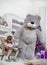 Little girl is reading a book next to a big gray teddy bear