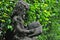 Little girl reading book statue in front of green tree wall in the garden