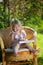 Little girl reading book in wicker chair outdoor