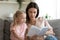 Little girl reading book with young mom