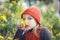 Little girl with red cap sniffing flowers.