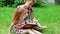 Little girl with red hair and her mother read book on lawn