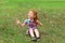Little girl with red hair sits on grass and catches bubbles