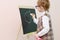 Little girl with red pigtails in glasses chalk draws