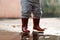 Little girl in red rainboots playing in puddle after rain. Happy fall childhood activity