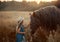 Little girl with red tinker horse in oats evening field