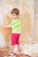 Little girl remove old wallpapers from wall