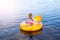 The little girl is resting in an inflatable chair on the water. The child is talking on the smartphone