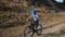 A little girl rides a Bicycle in a protective helmet near a hill in nature