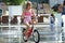 Little girl rides his bike among fountains