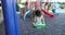 Little girl rides on swing on modern playground at daytime