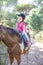 Little girl riding catching the reins of the horse in a forest