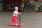 A little girl riding a children`s scooter in a skate Park