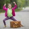 Little girl on the road with a suitcase and a Teddy bear.