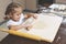 Little girl rolls out the dough with a small rolling pin