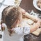 A little girl rolls out the dough using a wooden rolling pin